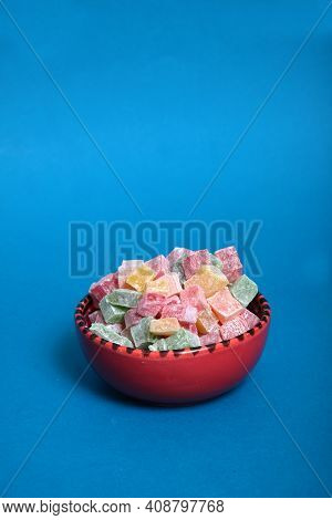 Red Bowl Of Multicolored Rahat Lakoum Isolated On Blue Background. Turkish Sweet Concept. Image Cont