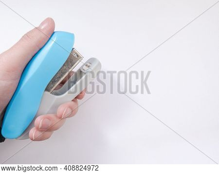 A Blue Paper Stapler Is Held In Your Hand. Blue Stapler Of The Paper. Stapler In Hand.
