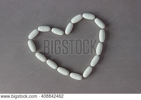 The Capsules Are Laid Out In The Shape Of A Heart On A Gray Background.