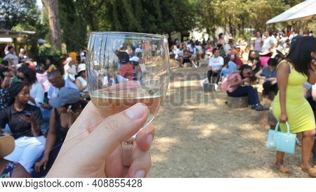 Johannesburg, South Africa - October 2019: Hand Holding A Glass Of White Wine In Fourways Farmers Ma