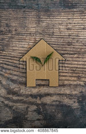 Green Home And Energy Efficiency, Ecological House Icon With Leaves On It On Wooden Background
