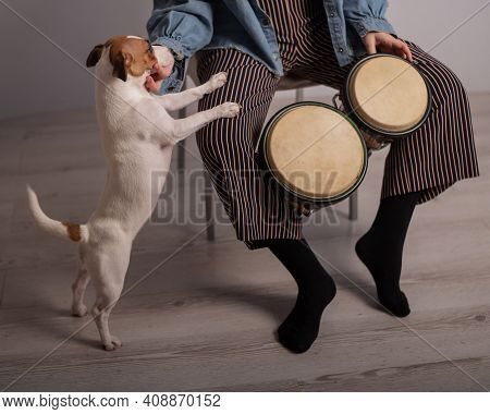 A Dog Is Standing By A Woman Playing Small Ethnic Drums