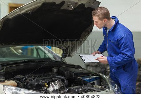 Férfi szerelő vágólappal autó motor vizsgálata