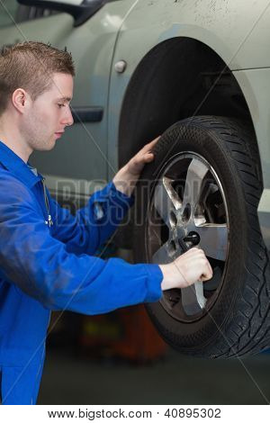 Mužské mechanik užívající klíč ke změně pneumatik automobilu
