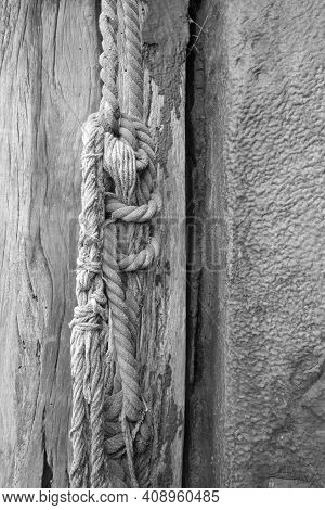 Black And White Image Of Old Nautical Rope Hanging From A Weathered Wooden Post At Old Leigh, Leigh-