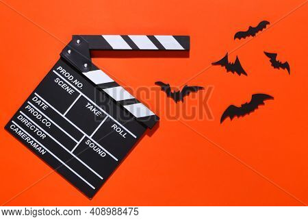 Horror Movie, Halloween Theme. Movie Clapperboard And Flying Decorative Bats On Brightorange Backgro