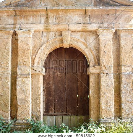 Old Brown Wooden Door In A Stone Wall