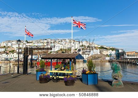 Colourful flowers and union jack flags at harbourside Brixham harbour Devon with blue sky