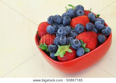 Strawberries and blueberries in bowl with copy space