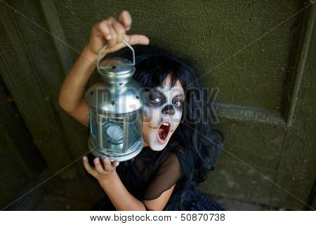 Portrait of Halloween girl with lantern looking at camera with frightening expression