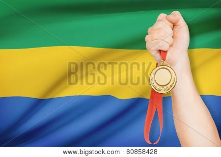 Medal In Hand With Flag On Background - Gabonese Republic