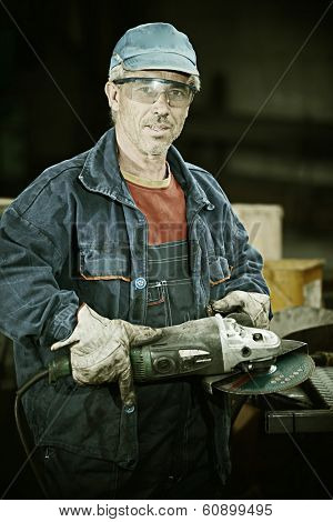 Industrial worker cutting and welding metal with many sharp sparks