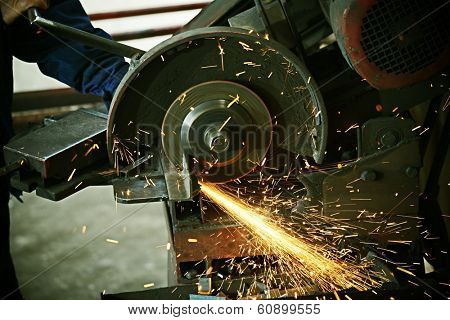 Industrial worker cutting and welding metal with many sharp sparks