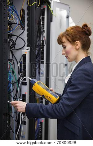 Technician using digital cable analyzer on server in large data center