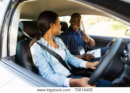 smiling driving instructor giving thumbs up to learner driver during test