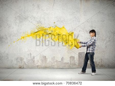 Young boy splashing colorful paint from bucket