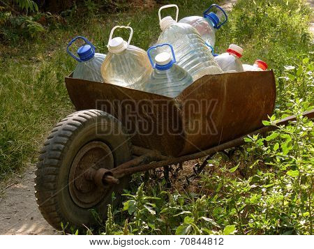 wheelbarrow full of plastic bottles with artesian water