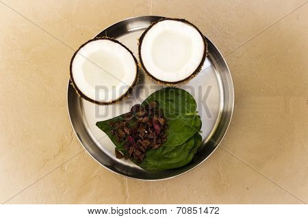A plate with coconut, betal leaves and pieces of areca nuts