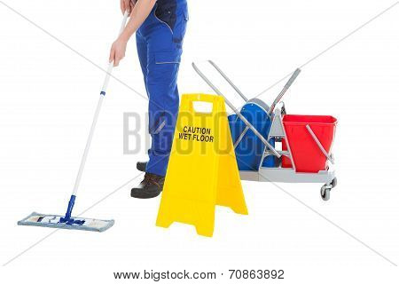 Low Section Of Servant Mopping Floor By Wet Floor Sign