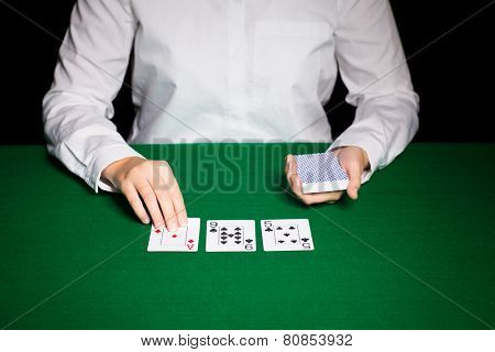casino, gambling, poker, people and entertainment concept - close up of holdem dealer with playing cards