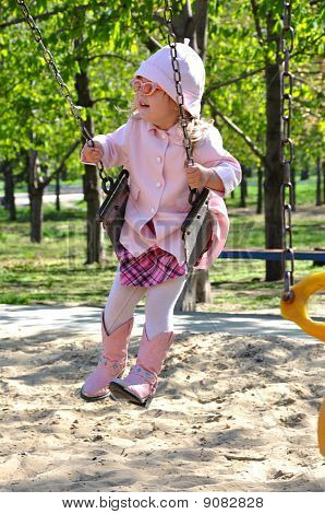 Menina bonito criança andando em balanço no parque infantil