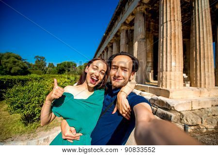 Young couple taking selfie picture with Hephaistos temple on background in Agora near Acropolis