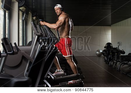 Mature Man Doing Aerobics Elliptical Walker In Gym