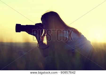 Photographer taking pictures with SLR camera at sunset