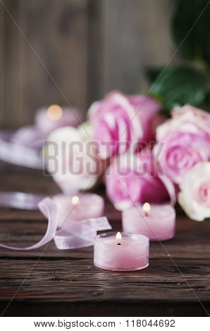 Pink Roses And Pinl Candles On The Wooden Table