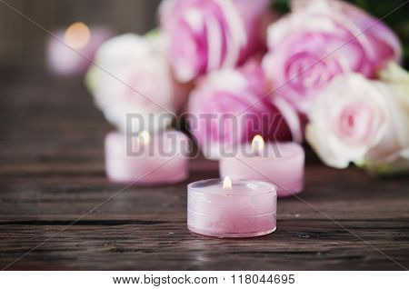 Pink Roses And Pinl Candles On The Wooden Table