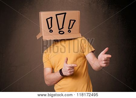 Young man standing and gesturing with a cardboard box on his head with exclamation point