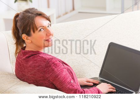 Deaf woman wearing hearing aid using laptop at home