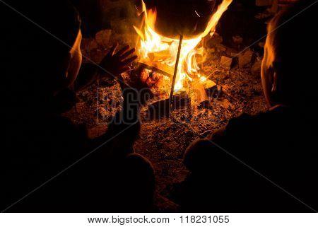 children sit around the campfire at night