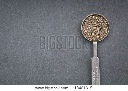 chia seed on metal measuring tablespoon against slate sone with a copy space