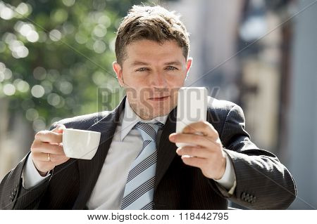 Attractive Businessman Sitting Outdoors In Coffee Break Using Mobile Phone Checking Onl¡ne News