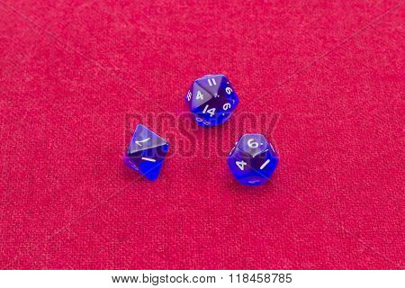 Three Polyhedral Role Playing Dice On Table With Red Cloth