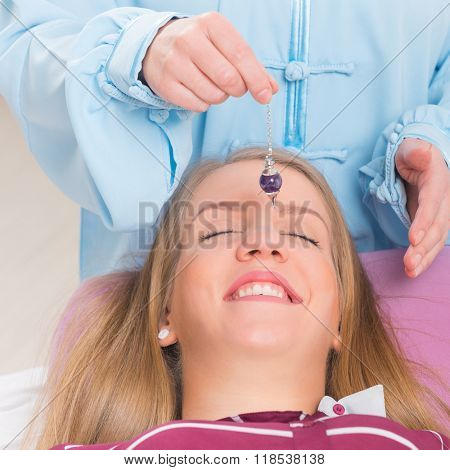 Alternative medicine therapist using pendulum to make a diagnosis