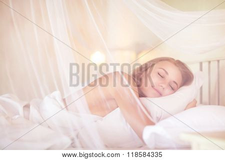 Gentle female sleeping in the bedroom under canopy, with pleasure relaxing in luxury spa resort, enjoying, calmness and harmony