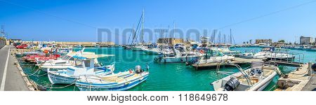 HERAKLION, CRETE, GREECE - AUGUST 11, 2013: Traditional Greek fishing boats and yachts parked in Heraklion harbour. Old Heraklion fortress on background is very popular place on Crete island