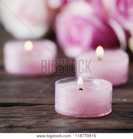 Pink Roses And Pinl Candles On The Wooden Table