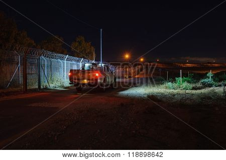 Watchman on the patrol road along the fence, at night