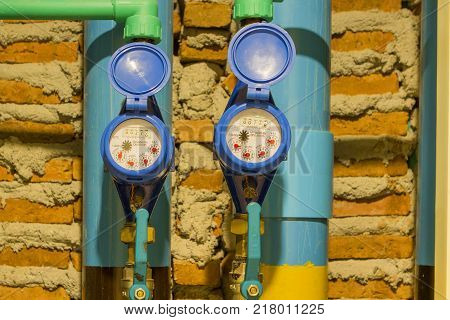Blue water meter with water pipe brick block background