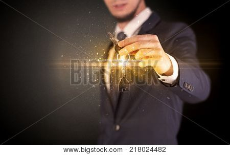 Businessman hand  over shiny keys in dark suit with dark background