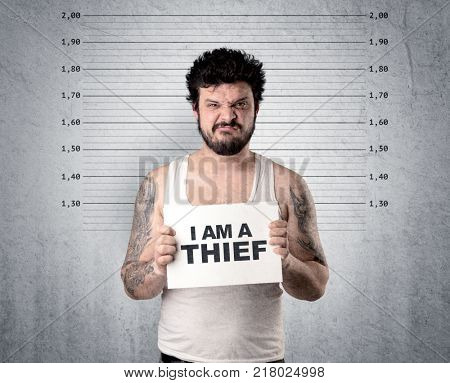 Caugth offender in front of a wall with table in his hand.