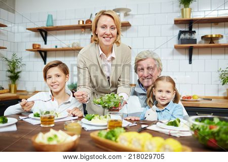 Hospitable grandparents and their grandchildren having breakfast in the kitchen