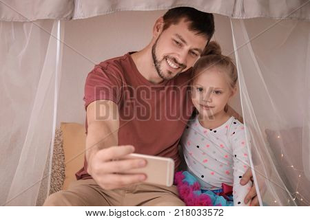 Father and his little daughter taking selfie in hovel at home