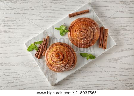 Marble board with sweet cinnamon rolls on table