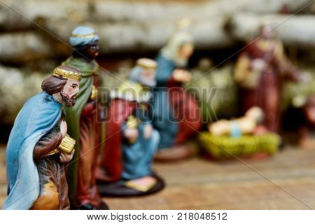 closeup of the three kings carrying their gifts adoring the Child Jesus on a rustic nativity scene