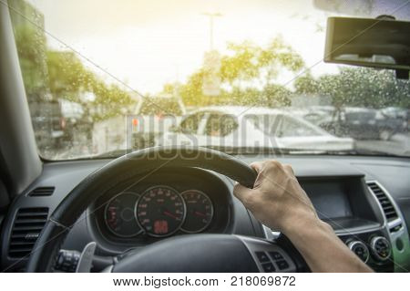 Traffic jam in the rush hour.Hand of a man driving car with traffic jam in rainy seasons.Rainy weather in road traffic. Risk of accident during rainy seasons