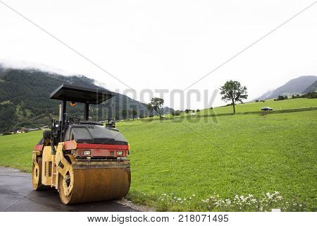 Road Roller machinery works outdoors at construction site at grass field near Burgusio or Burgeis village at Malles Venosta in val Venosta in Trentino-Alto Adige Italy